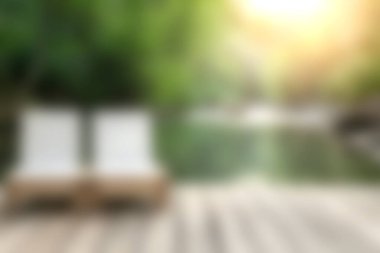 Sakin suların yanındaki şezlongların dinlenme ve huzur için mükemmel güneş ışığını ve yemyeşil suları yansıttığı sakin bir açık hava ortamının tadını çıkarın..