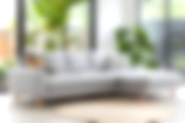 Çağdaş gri kanepe, yemyeşil bitkilerle bezenmiş, parlak ve açık bir oturma odasında rahat ve davetkar bir atmosfer yaratıyor..