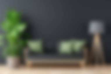 Yeşil yastıklarla süslenmiş şık bir kanepe, şık bir lamba ve rahat ve davetkar bir atmosfer yaratan canlı bir bitki içeren modern bir oturma odası sahnesi..