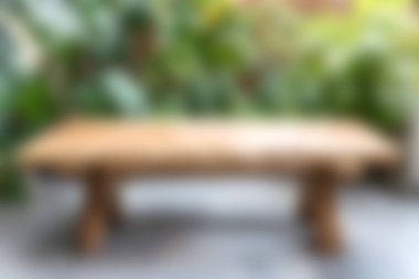 Kırsal bir ahşap masa, canlı yeşilliklerle çevrili, açık bir ortamda oturur. Yemek ve rahatlama için mükemmel sakin bir atmosfer sağlar..