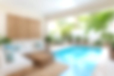 Bu görüntü, bereketli yeşil bitkilerle dolu parlak bir alanda serin ve davetkar bir atmosfer yaratarak rahatlama ve refah için dekore edilmiş şık bir kapalı yüzme havuzunu gösteriyor..