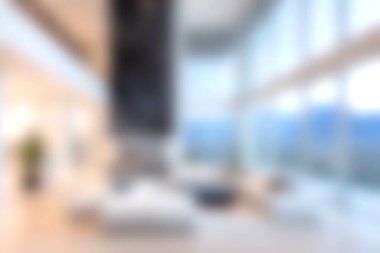 Modern bir minimalist oturma odası geniş pencereler ve çarpıcı dağ manzaraları sergiliyor. Bulanık odak dingin atmosferi ve zarif dekorasyonu arttırır..