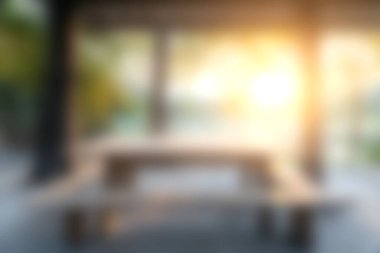 Sıcak bir açık hava yemek alanı yumuşak sabah ışığı altında ahşap bir masa sunar. Huzurlu bir ortamda sıcak ve davetkar bir ortam yaratır..