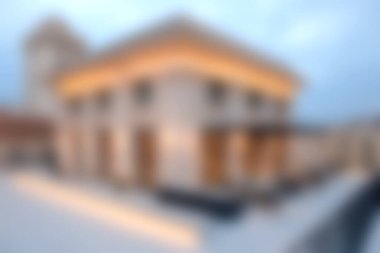 Bu görüntü, alacakaranlıkta yumuşak bir şekilde aydınlatılmış modern bir bina yakalıyor, zarif bir mimari ve şehir tasarımı sergiliyor. Huzur ve çağdaş biçim temaları için ideal.