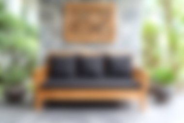 Siyah yastıklarla süslenmiş şık, ahşap bir kanepe, yemyeşil yemyeşil bir salonda, sakin ve davetkar bir atmosfer yaratıyor..