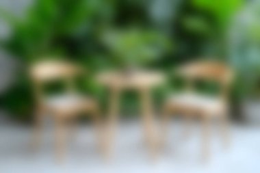 İçinde ahşap mobilyalar, küçük bir masa ve yemyeşil bitkilerle çevrili sandalyeler olan rahat bir kafe seti keşfedin..