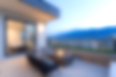 Modern mobilyaların olduğu sakin bir balkon sahnesi, rahatlamak için mükemmel. Dağların ve yumuşak akşam ışığının tadını çıkar, davetkar bir atmosfer yarat..