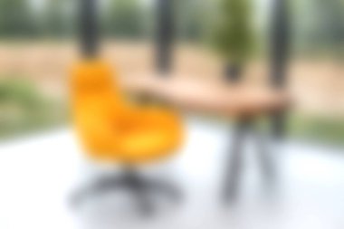 Parlak ve rahat bir modern çalışma alanı, yeşil manzaralı, ilham ve rahatlık için ideal, turuncu bir sandalye ve ahşap bir masa içerir..