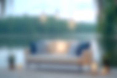 Bu görüntü, gölün kenarında, gün batımında rahat bir kanepede, yumuşak ışık ve doğal güzellikleri sergiliyor, dingin bir rahatlama alanı yaratıyor..