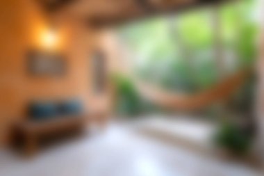 Bu görüntü, rahat bir kanepe ve huzurlu bir bahçe manzarasıyla rahat bir dinlenme ve sükunet ortamı sağlayan kapalı bir inziva görüntüsü yakalar..