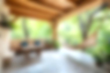 Bu resim, rahat bir açık hava oturma alanı, ahşap kirişler ve yemyeşil çevreyi saran, dinlenmek için sakin ve davetkar bir atmosfer yaratıyor..