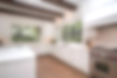 Bu resim, ahşap kirişler ve bol miktarda doğal ışığın yer aldığı modern bir mutfak içini gösteriyor. Minimalist tasarım temiz çizgileri ve şık bir atmosferi vurguluyor..