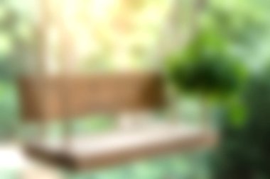 Yumuşak doğal ışık ve yemyeşil ile çevrili canlı bir bahçede sallanan güzel bir ahşap salıncak dinlenmek için huzurlu bir kaçış yaratır..