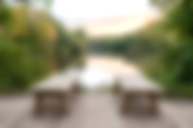 Bereketli yeşillik ve hafif ışıklandırmayla çevrili ahşap bankların bulunduğu sakin göl manzarası. Rahatlamak ve doğayı takdir etmek için ideal..