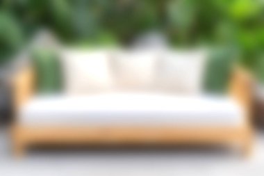 Rahat bir kanepede beyaz yastıklar ve yeşil atışlar sergilenir, canlı bir bahçe zeminine dayanır, rahatlama ve rahatlama için mükemmeldir..