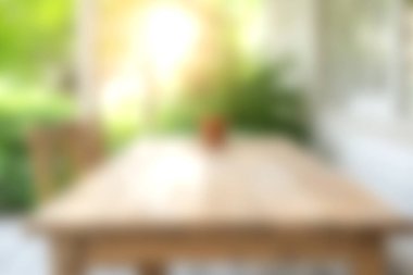 Güzel bir açık hava yemek alanı, ahşap bir masa, ılık güneş ışığı altında hafifçe bulanık, yemyeşil, dinlenmek için mükemmel sakin bir atmosfer yaratıyor..