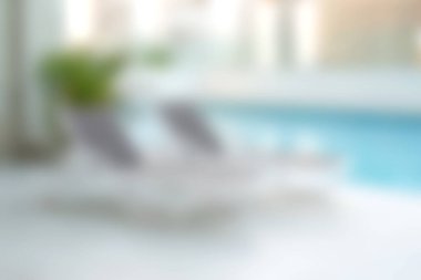 Bereketli yeşilliklerle çevrili, dinlenmek ve rahatlamak için ideal şezlongların olduğu huzurlu bir havuz kenarı sahnesi. Yaz tatili ya da spa günleri için mükemmel..