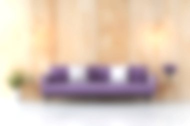 Modern mor bir kanepe zarif bir şekilde parlak bir oturma odasında oturur. Ahşap duvarlar, rahat yastıklar ve minimalist dekorlarla sıcak bir atmosfer yaratır..