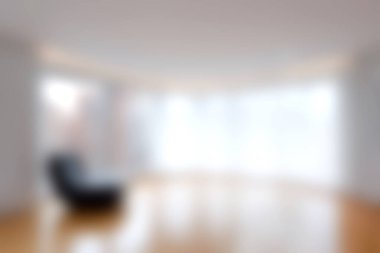 Zarif ahşap döşeme ve tek bir sandalyeyle tamamlanmış doğal ışığı davet eden geniş pencereli parlak ve havadar bir modern minimalist oturma odası..