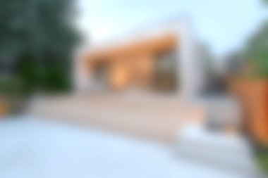 Huzurlu bir bahçe alanı ile çevrili ahşap bir güvertesi olan modern bir minimalist ev. Mimari tarzı konforla harmanlıyor, doğal ışığı davet ediyor..