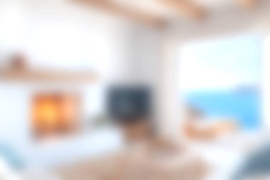 Bu resim, şöminenin bulunduğu rahat, parlak bir oturma odası ve açık pencereden büyüleyici bir deniz manzarası sergiliyor, davetkar bir atmosfer yaratıyor..