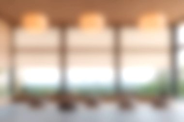 Bu resim, yumuşak ışıklandırmalı ve pencerelerin dışında bulanık doğal manzaralı rahat ve modern bir iç mekan içeriyor..