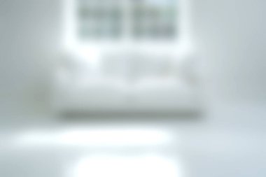 Yumuşak odaklı bir görüntüde, doğal ışıkla aydınlık bir odada beyaz bir kanepe sergileniyor, dinlenmek için mükemmel, sakin ve minimalist bir atmosfer yaratıyor..