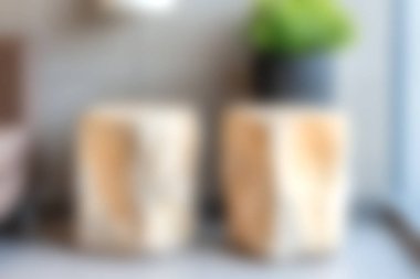 Eşsiz dokulara sahip iki kırsal ahşap blok bir saksı bitkisinin yanındaki modern bir masanın üzerinde oturur ve ev dekorasyon meraklıları için samimi ve davetkar bir atmosfer yaratır..