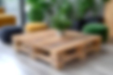 Kırsal bir ahşap sehpa ve saksı bitkisi modern bir oturma odasında odak noktası görevi görüyor. Yumuşak mobilyalar ve canlı renkler rahat atmosferi güçlendirir.