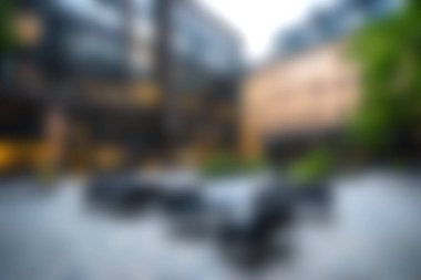 Bulanık binalar ve yemek masalarının yer aldığı sakin bir şehir avlusu, çağdaş bir ortamda rahatlama ve sosyal toplantılar için ideal..