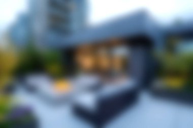 Bu resim, şehir ortamında yemyeşil renkli mobilyalarla çevrili, rahatlamak için tasarlanmış zarif bir açık hava yaşam alanını sergiliyor..