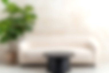 Şık bir oturma odasında yumuşak bej bir kanepe ve yemyeşil ile tamamlanmış eşsiz siyah bir kahve masası bulunur..