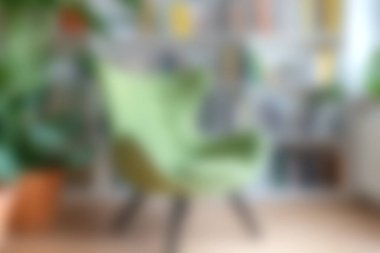 Rahat yeşil bir sandalye şık bir oturma odasında duruyor bitkilerle süslenmiş, canlı bir dekor, modern rahatlık ve davetkar bir atmosfer sunuyor..