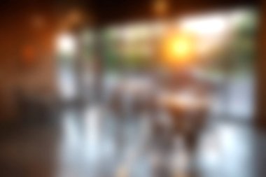 Sıcak günbatımı ışığının geniş pencerelerden içeri aktığı samimi, modern bir kafe sahnesi. Atmosfer rahatlamaya ve sosyalleşmeye davetiye çıkarır. Yaşam tarzı temaları için mükemmel.