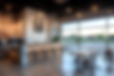 Stylish and modern cafe interior featuring large windows that allow natural light, creating a warm and inviting atmosphere perfect for relaxation and social gatherings.