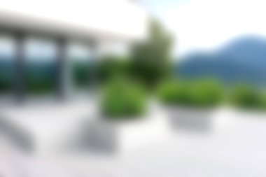 A serene modern outdoor terrace showcasing lush greenery and a stunning mountain view under a bright sunny sky, perfect for relaxation.