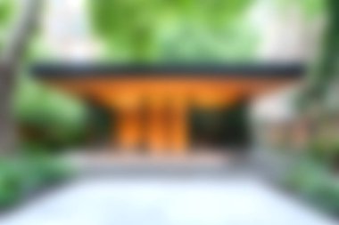 A serene urban garden featuring a modern pavilion amidst lush greenery. The soft-focus effect creates a peaceful atmosphere, inviting relaxation and reflection.