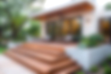 Yeşilliklerle çevrili zarif ahşap basamakları olan çarpıcı modern bir ev girişi. Doğal ışık davetkar bir atmosfer yaratır, rahatlamak için mükemmeldir..