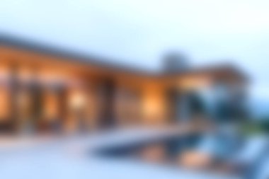 Günbatımında bir yüzme havuzu olan modern lüks bir villanın çarpıcı bir görüntüsü. Zarif mimari ve açık hava mekanları sergileniyor..