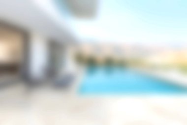 Parlak ve berrak mavi gökyüzünün altında açık alanları davet eden el değmemiş bir yüzme havuzu olan modern bir villanın çarpıcı manzarası..