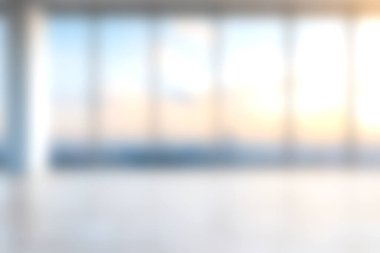 Doğal ışığı teşvik eden, yaratıcılık ve üretkenliği teşvik eden geniş tabandan tavana pencereli sakin ve parlak bir modern ofis alanı.