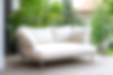 Şık beyaz bir kanepe, canlı yeşillik ve yumuşak doğal ışıkla çevrili bir terasta sergileniyor. Rahatlamayı ve zarif açık havada yaşamayı vurguluyor..