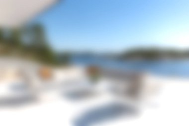 Bu resim, deniz kenarındaki sakin bir açık hava salonunu gösteriyor. Güneş ışığı ve modern mobilyalarla dolu. Rahatlamak ve dinlenmek için mükemmel..