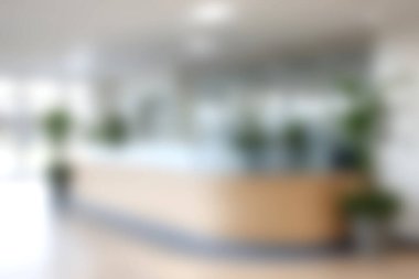 Bu görüntüde modern bir ofis lobisi var. Bir resepsiyon masası ve kapalı alandaki bitkiler parlak ve davetkar bir atmosfer yaratıyor. İş temaları için mükemmel.