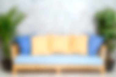 Mavi ve sarı yastıklı şık bir kanepenin olduğu rahat bir oturma odası sahnesi, bereketli kapalı yer bitkilerinin yanında, rahatlama için mükemmel bir karşılama atmosferi yaratıyor..