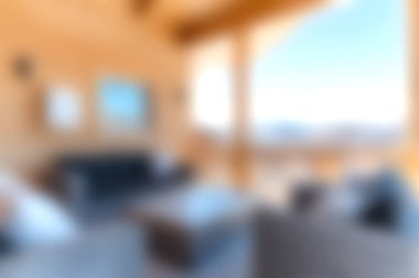 Bu resim, güzel dağ manzaraları ve doğal ahşap aksanlar sunan geniş pencereli rahat ve modern bir oturma odasını gösteriyor. Geri çekilmek için mükemmel..