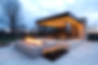 Alacakaranlıkta ışıklandırılmış, mükemmel bir akşam inzivası için sükunetle harmanlanmış rahat bir açık hava yaşam alanı içeren modern bir mimari tasarım..