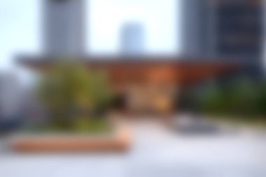 Çağdaş tasarım elementleri ve yeşillik içeren modern bir şehir girişinin bulanık görüntüsü. Barışçıl bir atmosfer mimariyle doğayı harmanlar..