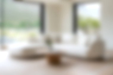 Yumuşak mobilyaları olan güzel tasarlanmış bir oturma odası, doğal ışığı davet eden büyük pencereler, ve minimalist dekorlar, sıcak ve davetkar bir atmosfer yaratıyor..