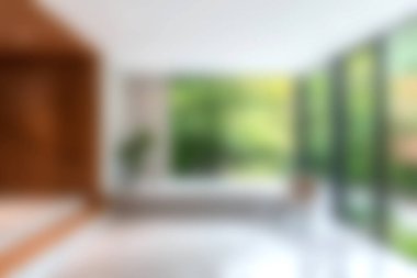 Bu resim, geniş pencereli modern bir minimalist yaşam alanını sergiliyor. Serin yeşillik manzarası sunuyor, sakin ve davetkar bir atmosfer yaratıyor..